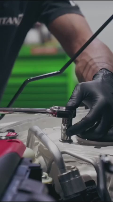 Mechanic using SureSafe Obsidian black nitrile gloves for engine work, brake repair, and tire maintenance.